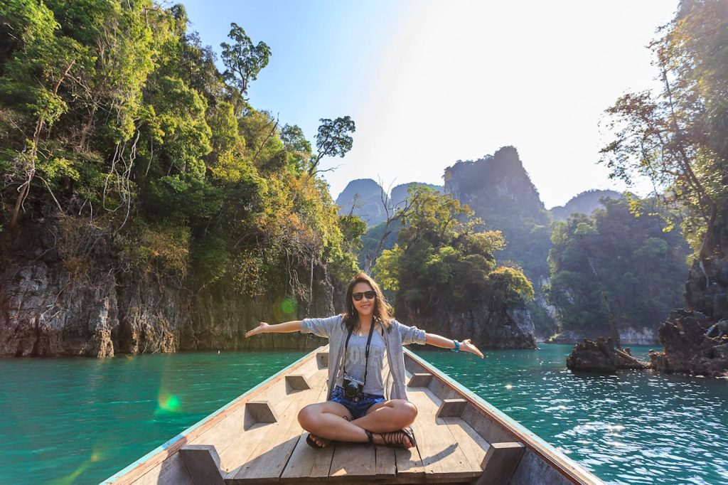 Asian woman relishing a serene boat journey through the lush karst landscape of Thailands Khlong Sok.